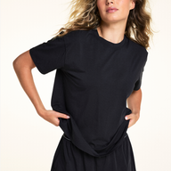 In a studio close-up, Alexis wears the Cloud Cotton Short in Black, featuring a relaxed fit, soft elastic waistband with Harper Wilde logo detailing, side pockets, and a functional button fly.