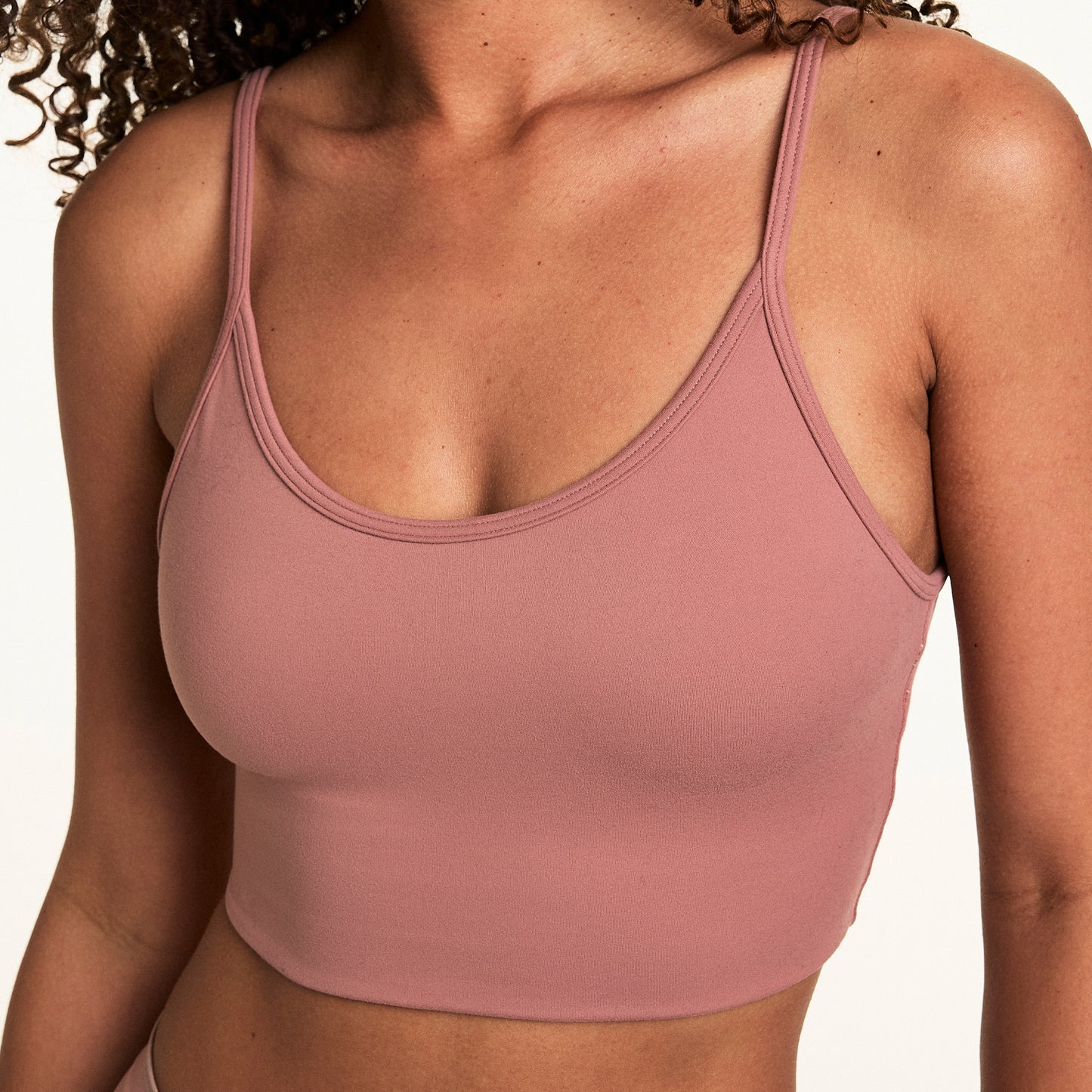 On a light studio backdrop, Courtney wears the Whipped Knit Scoop Bralette in Plum. The longline bralette features a scoop neckline, thin straps, and soft knit fabric for lightweight everyday comfort.