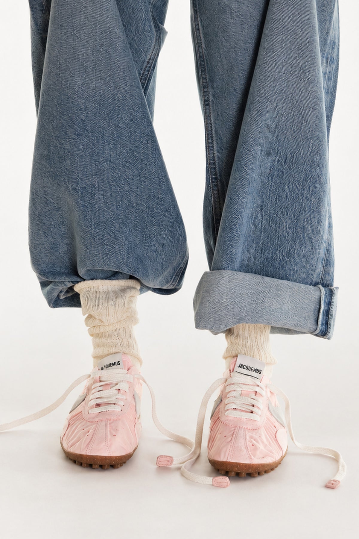 On-model shot of white crew socks with a navy stripe, styled with red sneakers and rolled dark denim.