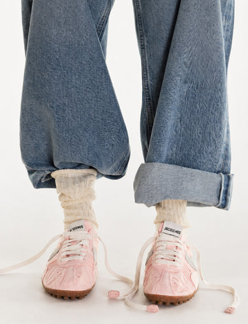 On-model shot of white crew socks with a navy stripe, styled with red sneakers and rolled dark denim.