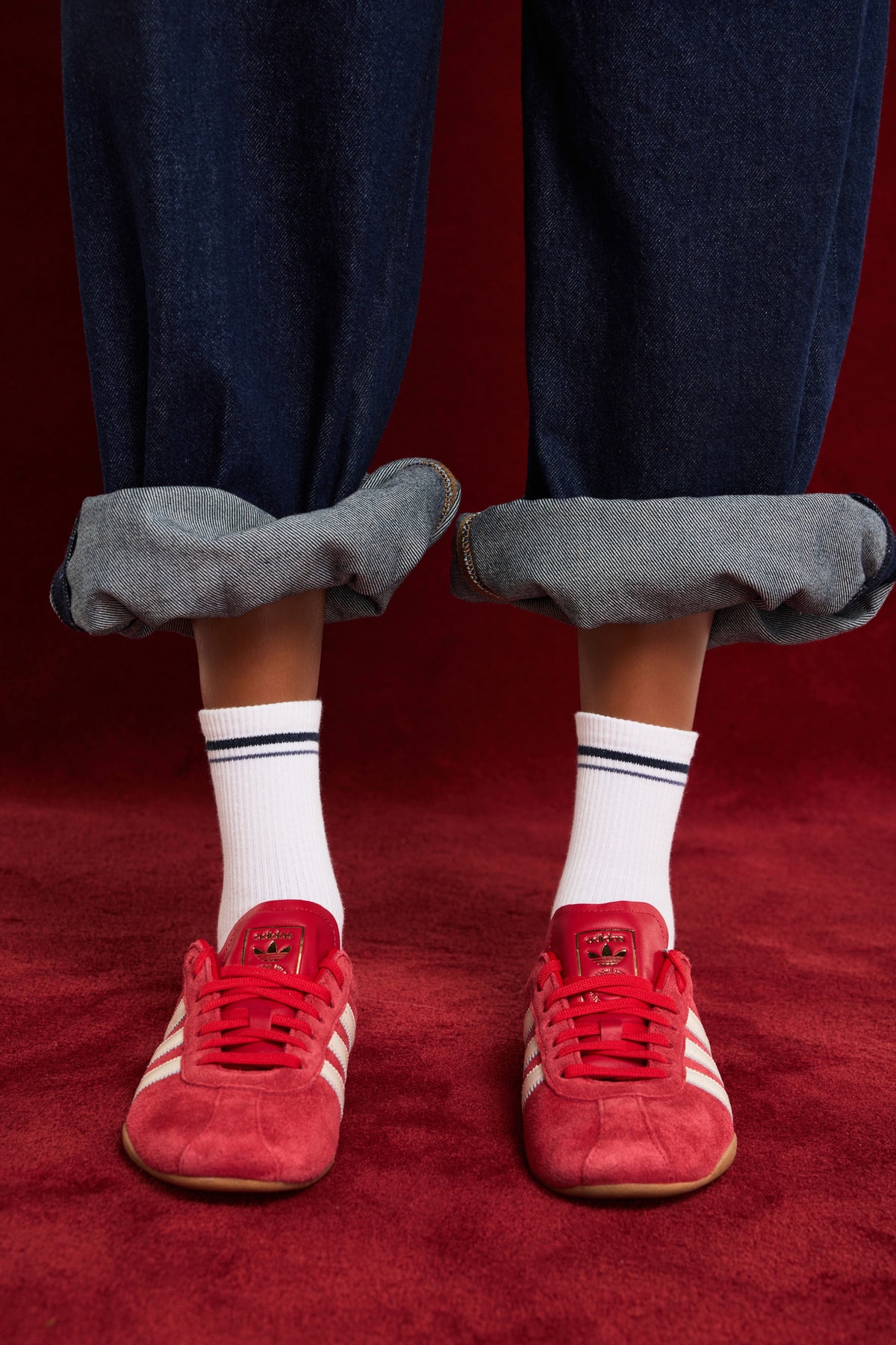 On-model shot of cream ribbed crew socks, styled with pink sneakers and rolled light denim.