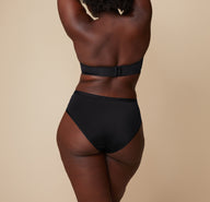 A back view of Akesha in the Bliss Hiphugger, focusing on the coverage and fit of the waistband and the overall silhouette from behind.