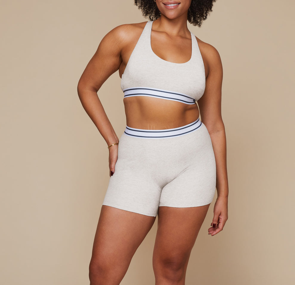 Model standing with her arms at her side wearing the Cloud Cotton Logo Racerback Bralette and matching Cloud Cotton Logo Boxer Brief in the color Heather Oatmeal. sizing: Alexandra wears size XL