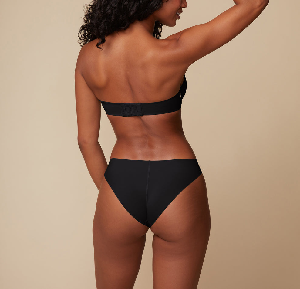Back view of model Ally wearing the Base Strapless Bra and No-Show Bikini in Black, displaying the seamless fit of the bikini and supportive back band of the strapless bra.