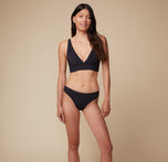 Model Anna stands facing forward in the Bliss Plunge Adjustable Bralette and Bliss Bikini in Black, with a relaxed stance.