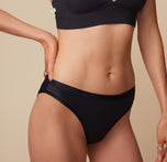 Close-up of model Anna’s midsection in the Bliss Plunge Adjustable Bralette and Bliss Bikini in Black, focusing on the mid rise of the bikini. sizing: Anna wears size Small