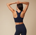 Anna in the Flex Tank and Flex High Rise Leggings in Ink, with arms stretched above her head, showcasing the back of the racerback tank.
