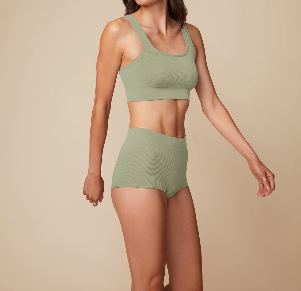 Model Anna stands facing forward in the Lounge Boyshort in Sage, with arms relaxed at her sides, highlighting the high-waist fit and ribbed texture.
