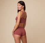 Anna is shown from the side, displaying the back view of the Lounge Rib Scoop Bralette and Lounge Rib Boyshort in Clay.