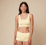 Model Anna stands smiling in the Lounge Scoop Bralette and Lounge Rib Boyshort in Sunnyside, highlighting the bright, comfortable fit of both pieces.