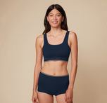 Model Anna stands facing forward in the Lounge Scoop Bralette and Lounge Boyshort in True Blue, with arms relaxed at her sides, showcasing the ribbed texture.