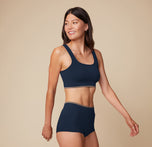 Side view of model Anna in the Lounge Scoop Bralette and Lounge Boyshort in True Blue, slightly angled with one arm swinging back, highlighting the ribbed fabric and comfy fit. sizing: Anna wears size Small
