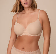 Sonnie wearing the Base Lace T-Shirt Bra in Beige. The image shows a front view of the bra's lightly lined cups and scalloped lace trim, highlighting its smooth microfiber fabric and supportive underwire design. sizing: Sonnie wears size 36E