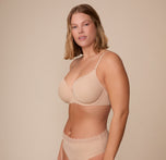 Sonnie in a three quarter view pose wearing the Base Lace T-Shirt Bra and Bliss Lace Highwaist Brief in Beige. This angle emphasizes the smooth silhouette, seamless lightly lined cups, and soft stretch lace detail along the band.