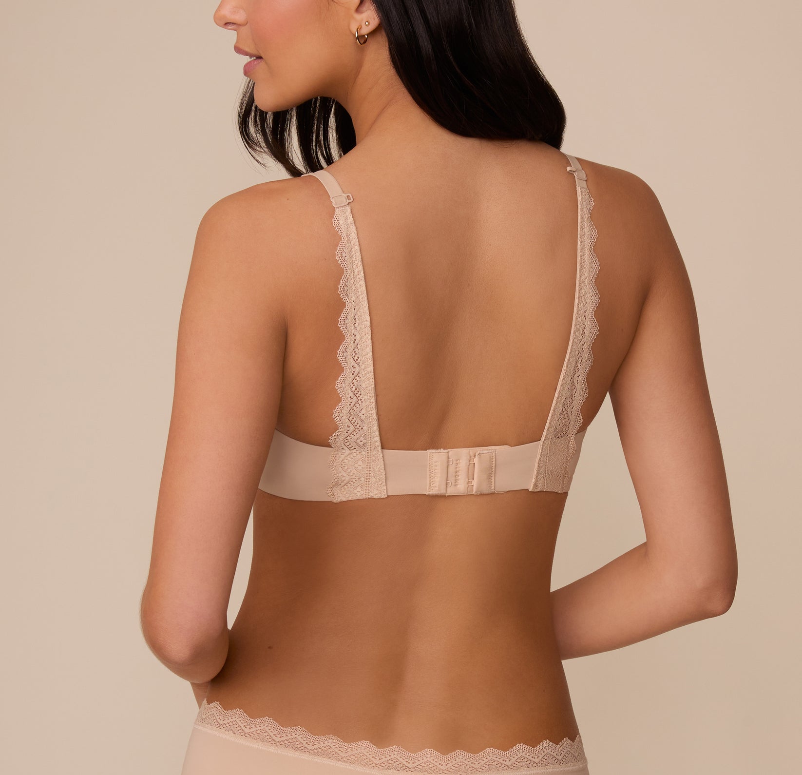 Back view of Marcela in the Base Lace T-Shirt Bra in Beige. The image shows lace-trimmed straps and a secure hook-and-eye closure, designed for support and racerback conversion.