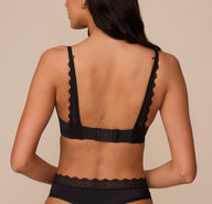 Marcela shown from the back in the Base Lace T-Shirt Bra in Black. The lace-trimmed straps and hook-and-eye closure are visible, offering support with convertible racerback capability.