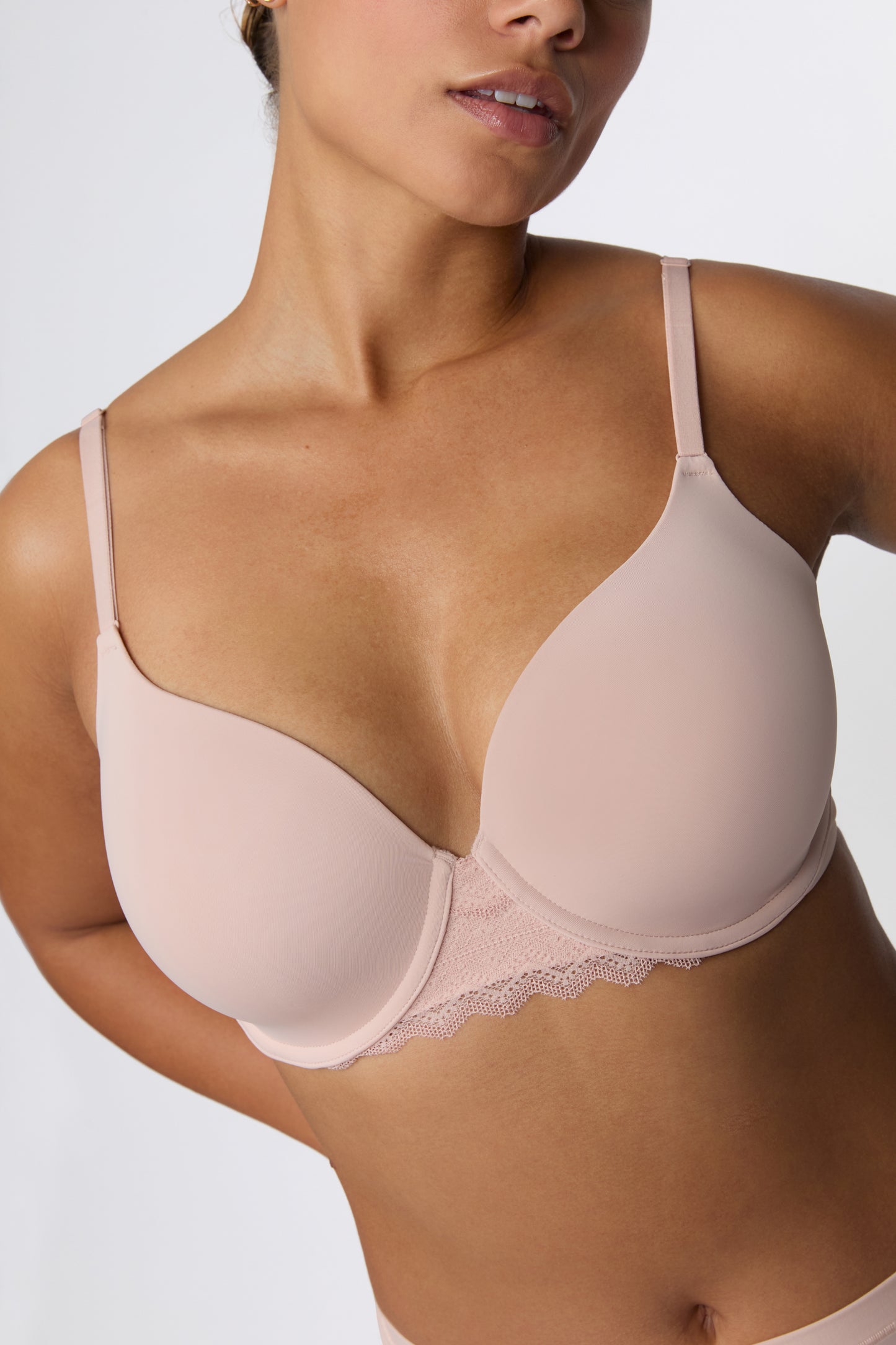 In a studio with a light gray backdrop, India wears the Base Lace Bra in Ember Rose, showing the lightly lined underwire cups, smooth microfiber fabric, and lace trim along the band. sizing: India wears size 36D