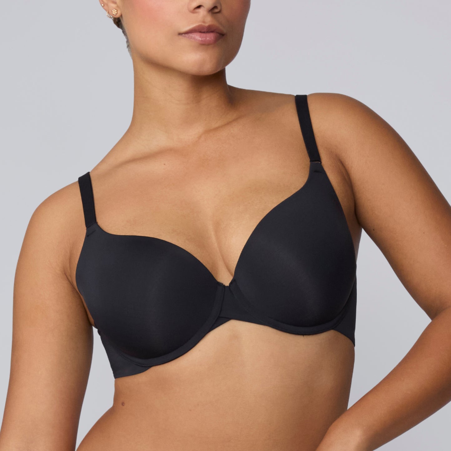 Against a light grey background, India models the Base Push-Up Bra in Black from the front. The molded push-up cups provide defined lift, finished with a smooth microfiber band and adjustable straps.