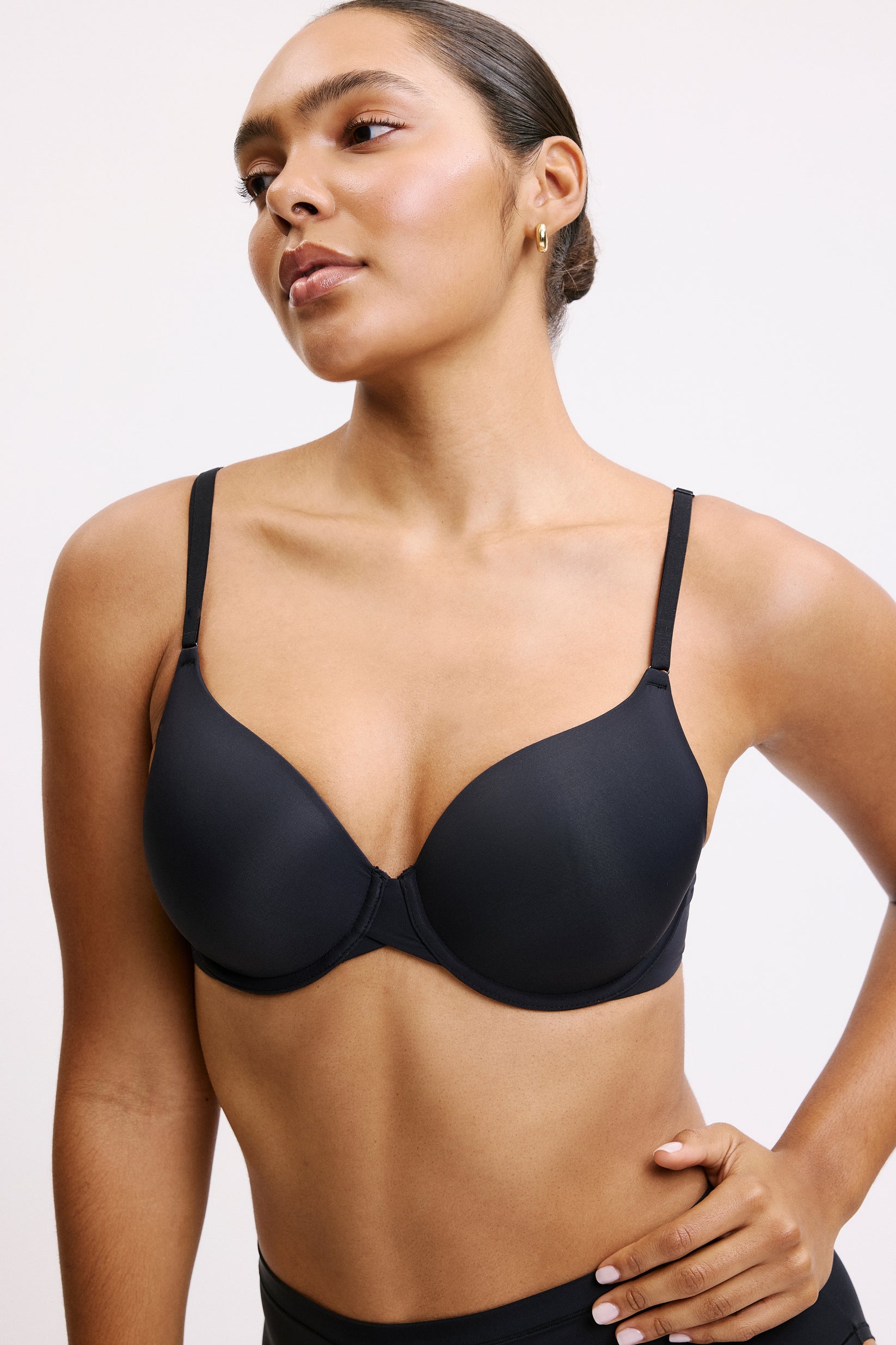 Against a light gray studio backdrop, Amber wears the Base T-Shirt Bra in Black. The lightly lined, full-coverage underwire cups create a smooth silhouette, finished with thin front-adjusting straps and Harper Wilde’s signature silky-soft microfiber fabric. sizing: Amber wears size 34D
