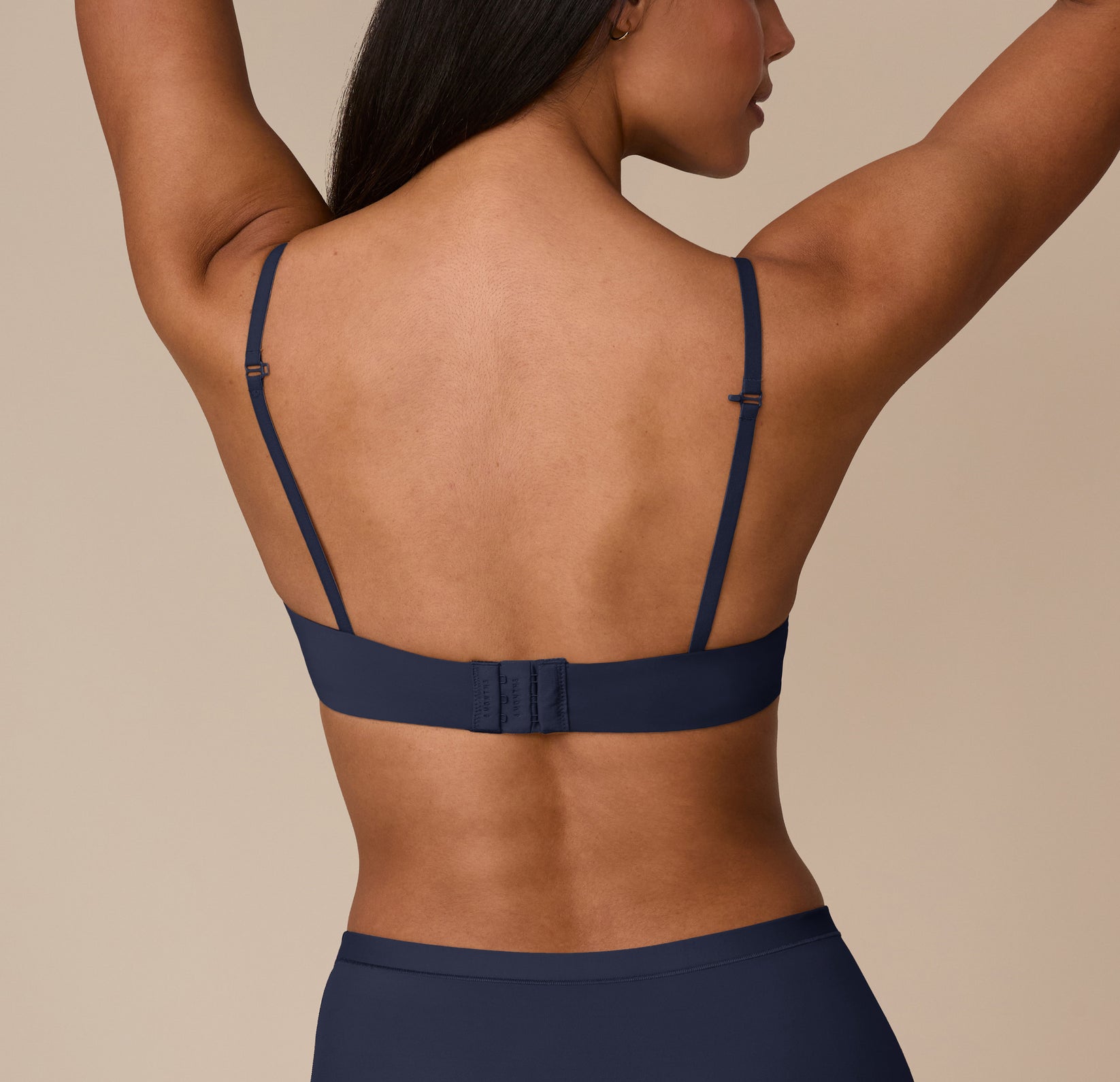 Back view of Nemesis wearing the Base T-Shirt Bra in True Blue. The image shows the smooth band and the J-hook for a convertible racerback feature.