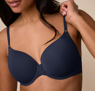 Close-up of Nemesis adjusting the front strap of the Base T-Shirt Bra in True Blue, emphasizing the convenient front-adjusting strap feature.
