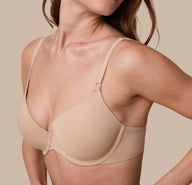 A close-up of Gracie in the Base T-Shirt Bra in Beige, focusing on the silky-smooth fabric, front-adjusting straps, and seamless construction.
