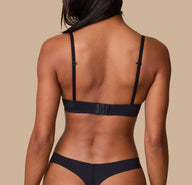 Ally showcases the back of the Base T-Shirt Bra in Black, emphasizing the adjustable hook-and-eye closure and slim, supportive straps.