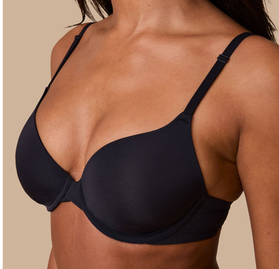 A close-up of Ally modeling the Base T-Shirt Bra in Black, focusing on the smooth, ultra soft fabric, front adjustable straps, and supportive underwire structure.