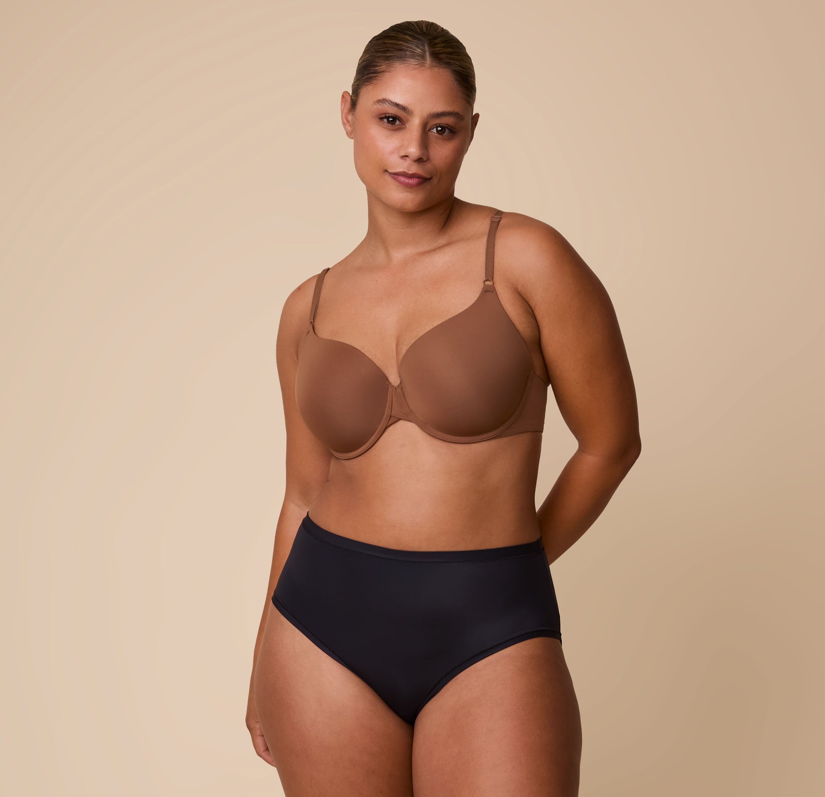Full-body image of India wearing the Base T-Shirt Bra in Brown, showcasing the bra’s front adjustable straps and supportive fit.