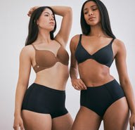 Emersyn and Ally model different shades of the Base T-Shirt Bra, with Emersyn wearing the Base T-Shirt Bra in Brown and Ally wearing the same bra in black, posing together to highlight the range of color options.