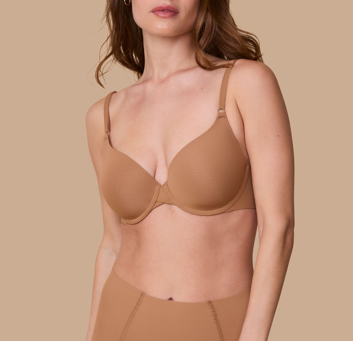 Gracie models the Base T-Shirt Bra in Tan, showcasing a front view of the bra's smooth, seamless design with lightly padded cups and adjustable straps. sizing: Gracie wears size 32D