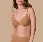 Gracie models the Base T-Shirt Bra in Tan, showcasing a front view of the bra's smooth, seamless design with lightly padded cups and adjustable straps. sizing: Gracie wears size 32D