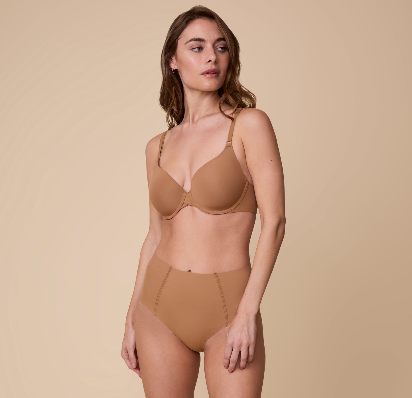 Full-body image of Gracie wearing the Base T-Shirt Bra in Tan with the matching No-Show Highwaist Brief, emphasizing the bra’s comfortable and supportive fit.
