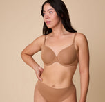 Emersyn wears the Base T-Shirt Bra in Tan, posing in a relaxed stance to showcase the smooth, form-fitting design of the bra. sizing: Emersyn wears size 36C