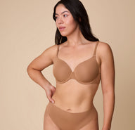 Emersyn wears the Base T-Shirt Bra in Tan, posing in a relaxed stance to showcase the smooth, form-fitting design of the bra. sizing: Emersyn wears size 36C
