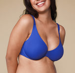 Close-up of the Base Unlined Bra in Deja Blue worn by a smiling Claudia. The image focuses on the bra’s unlined design and vibrant color.