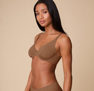 Side profile of Ally wearing the Base Unlined Bra in Brown, showing the wireless cups and front-adjusting straps designed for an easy, customized fit.