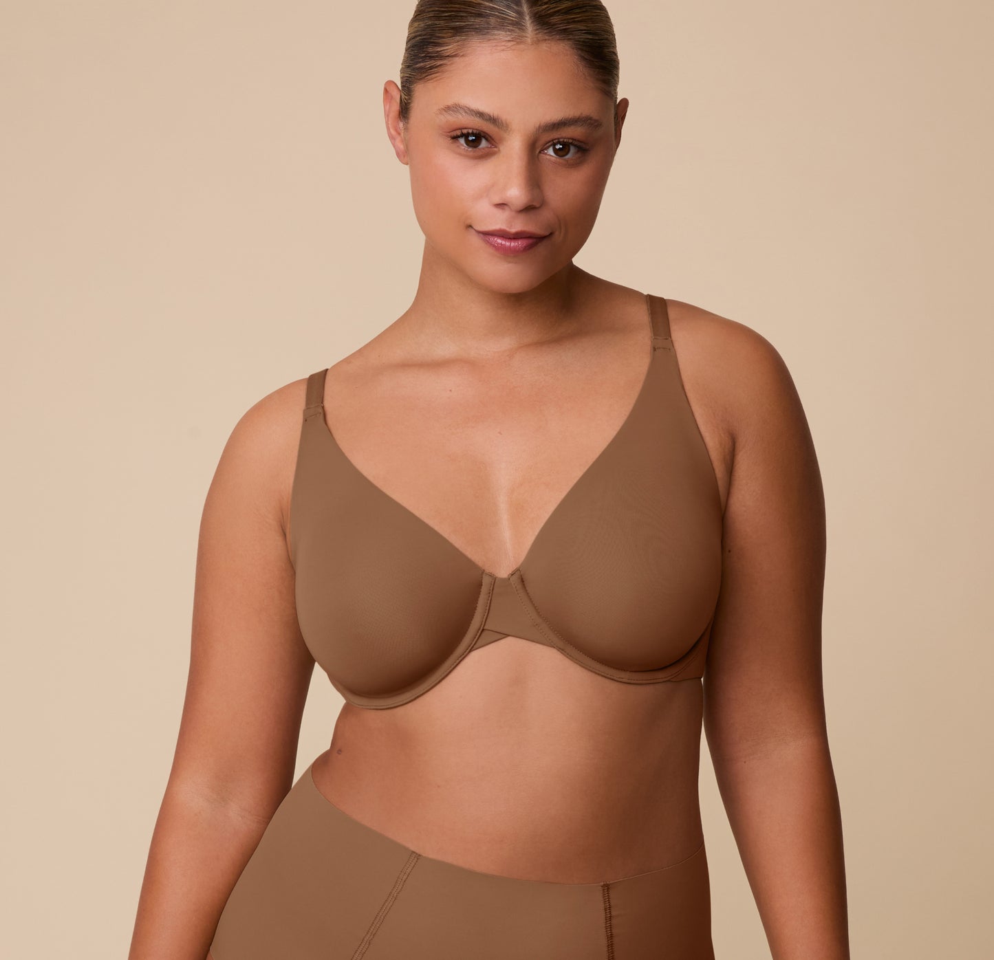 India faces forward wearing the Base Unlined Bra in Brown, showing the bra’s natural shape and full-coverage fit, designed to feel like wearing nothing at all. sizing: India wears size 36C