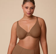 India faces forward wearing the Base Unlined Bra in Brown, showing the bra’s natural shape and full-coverage fit, designed to feel like wearing nothing at all. sizing: India wears size 36C