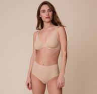 Gracie stands wearing the Base Unlined Bra in Beige with the coordinating No-Show Highwaist Brief, displaying the bra’s sleek, everyday fit.