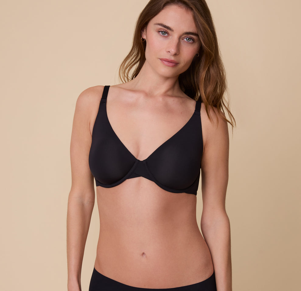 Gracie models the Base Unlined Bra in Black in a front-facing pose, highlighting the sleek, supportive design. sizing: Gracie wears size 32D