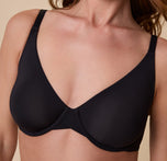 A close-up of Gracie wearing the Base Unlined Bra in Black, emphasizing the soft, seamless, unpadded cups and comfortable underwire support.
