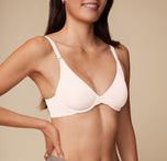 An up close shot of Anna wearing the Base Unlined Bra in Quartz. The plunging neckline, unlined cups, and front adjustable straps are emphasized. 