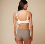 A back angle shot of Anna wearing the Base Unlined Bra in Quartz. The Racerback feature and thick, comfortable band are emphasized. 