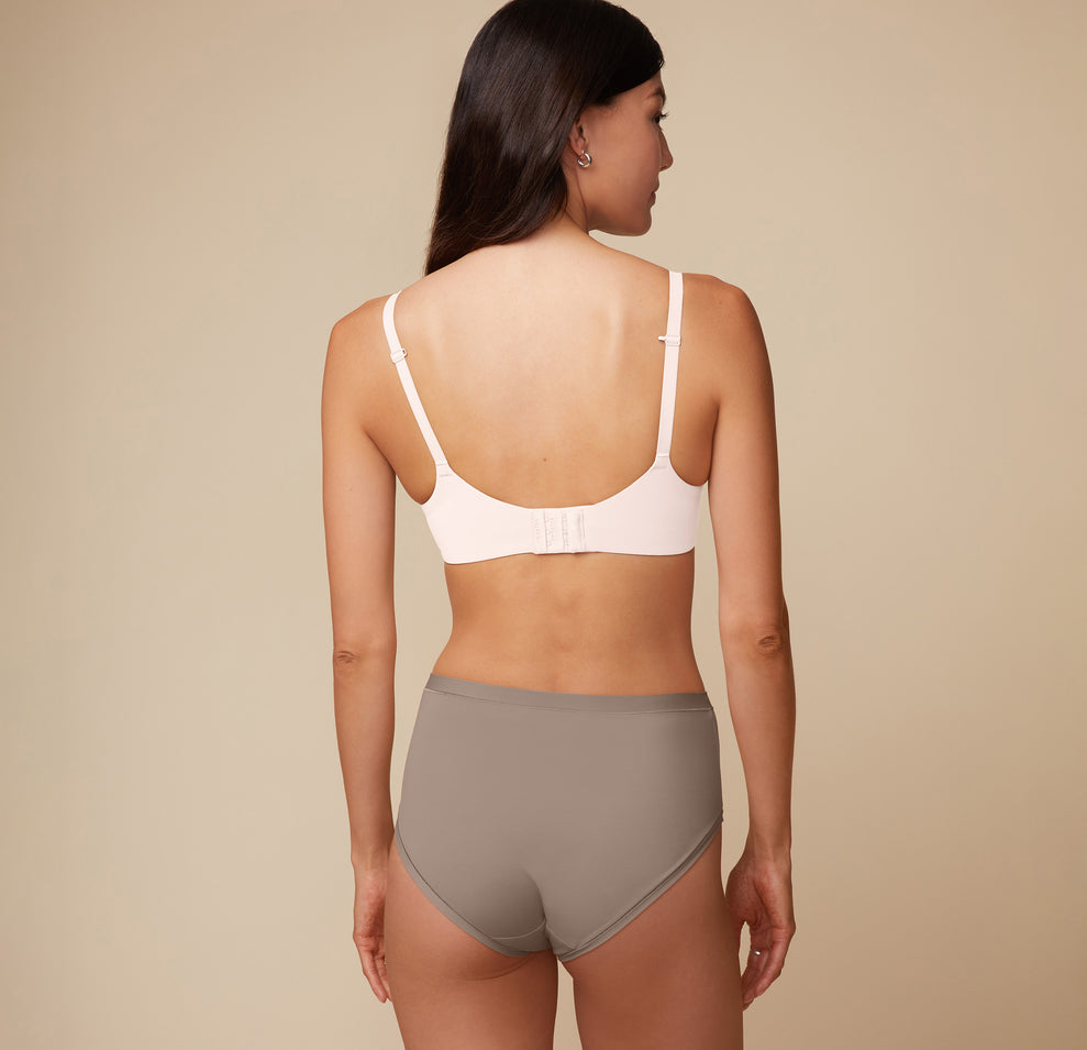 A back angle shot of Anna wearing the Base Unlined Bra in Quartz. The Racerback feature and thick, comfortable band are emphasized. 