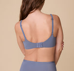 A back view of Gracie wearing the Base Unlined Bra in Steel, showcasing the adjustable straps, convertible racerback feature, and hook-and-eye closure for a customizable fit.