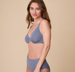 Gracie poses in a side view, displaying the sleek and seamless design of the Base Unlined Bra in Steel, made for everyday comfort.