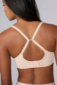 In a studio with a light gray backdrop, Amber wears the Base Unlined Bra in Rose from the back, showing the adjustable straps, sliding J-hook racerback conversion, and hook-and-eye closure.
