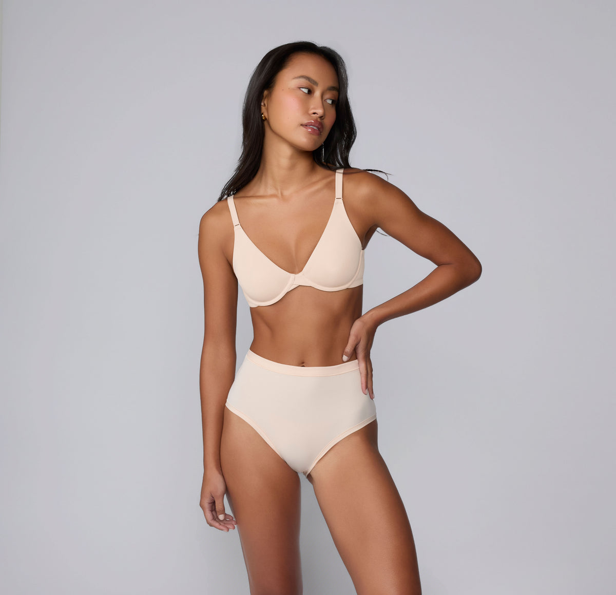 On a light gray studio backdrop, Amber wears the Bliss Highwaist in Rose with the Base Unlined Bra in Rose. Shown in a full-body view, the high-waisted underwear features a smooth waistband, full coverage, and soft microfiber fabric designed for comfortable, everyday wear with a no-show feel under clothing.