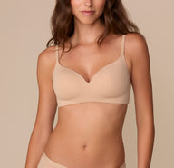 Front view of Alexis wearing the Base Wirefree T-Shirt Bra in Beige. The lightly lined cups and microfiber fabric create a smooth, seamless look with thin, adjustable straps. sizing: Alexis wears size 32D
